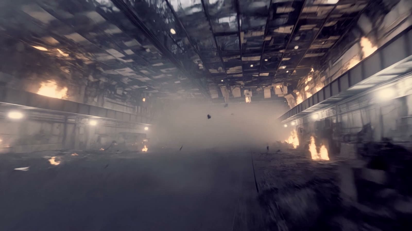 A wrecked industrial hall full of smoke, with fires burning along both walls