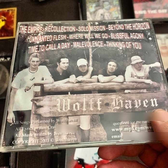 Back cover of the 2003 Wolffhaven CD: five band members leaning on a wooden Wolff Haven sign, with the ten track titles above